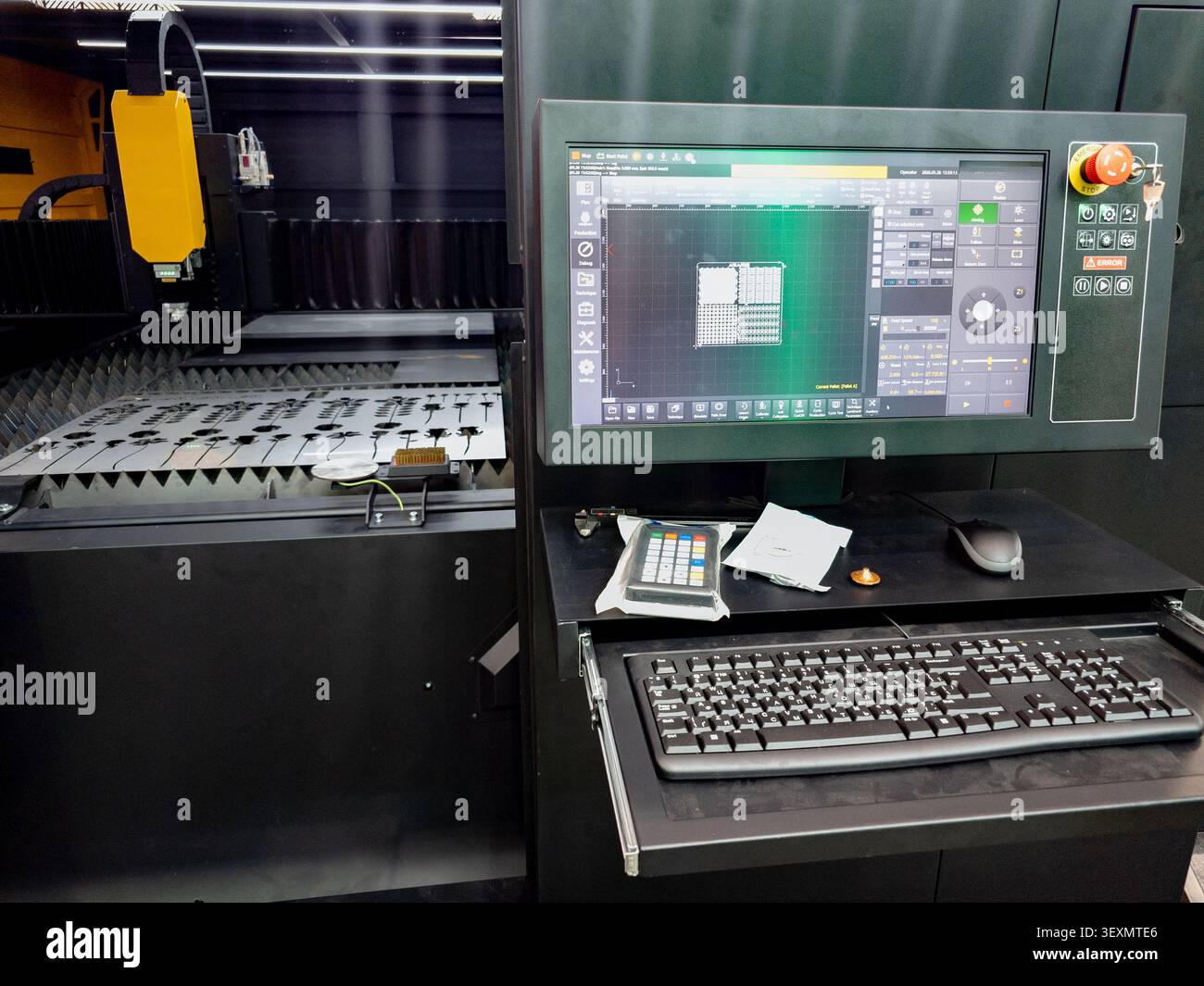 Modern CNC fiber laser cutter machine equipped with a digital control system, displaying software layout next to the cutting bed with metal sheets. Stock Photo