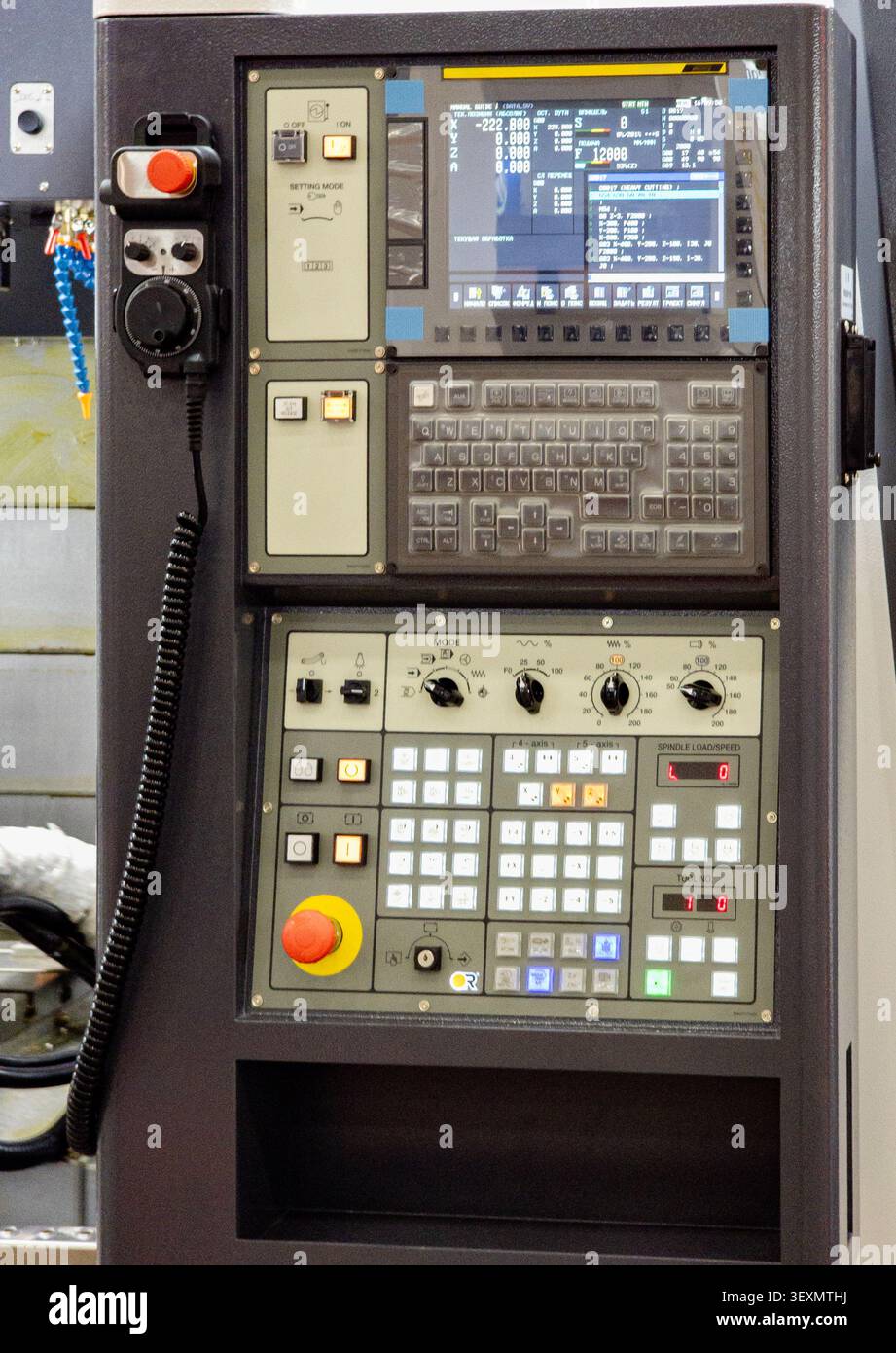 A close-up view of a modern computer numerical control (CNC) machine control panel, featuring a display screen, keyboard interface, adjustment dials, Stock Photo
