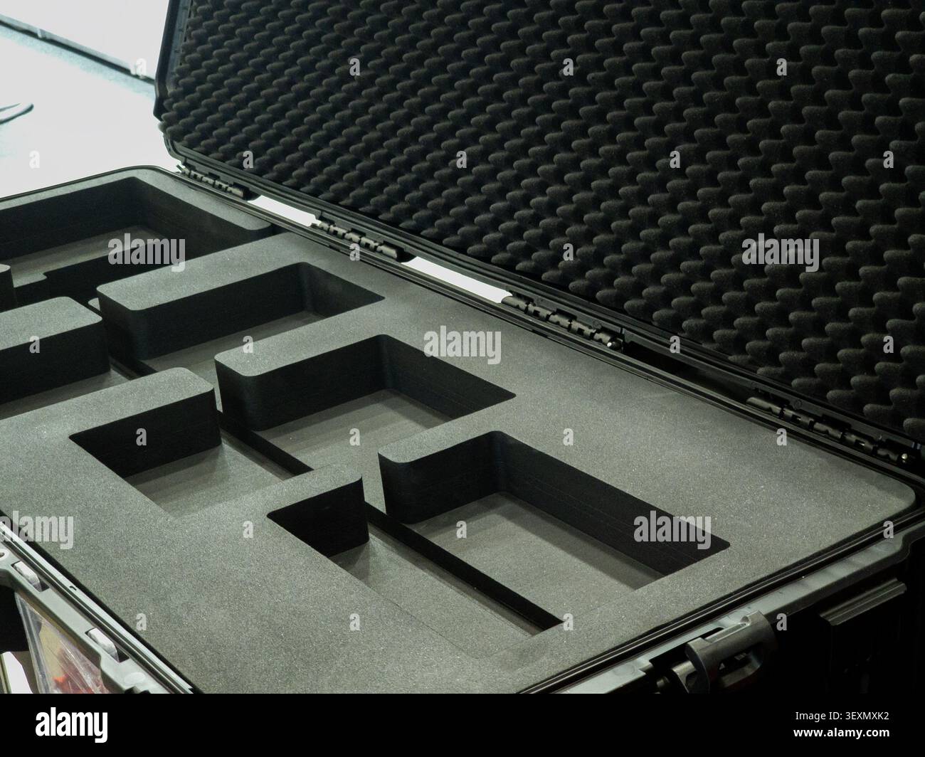 An open heavy-duty hard plastic protective flight case showing customized black foam compartments and egg-crate foam lining on the lid, designed for s Stock Photo