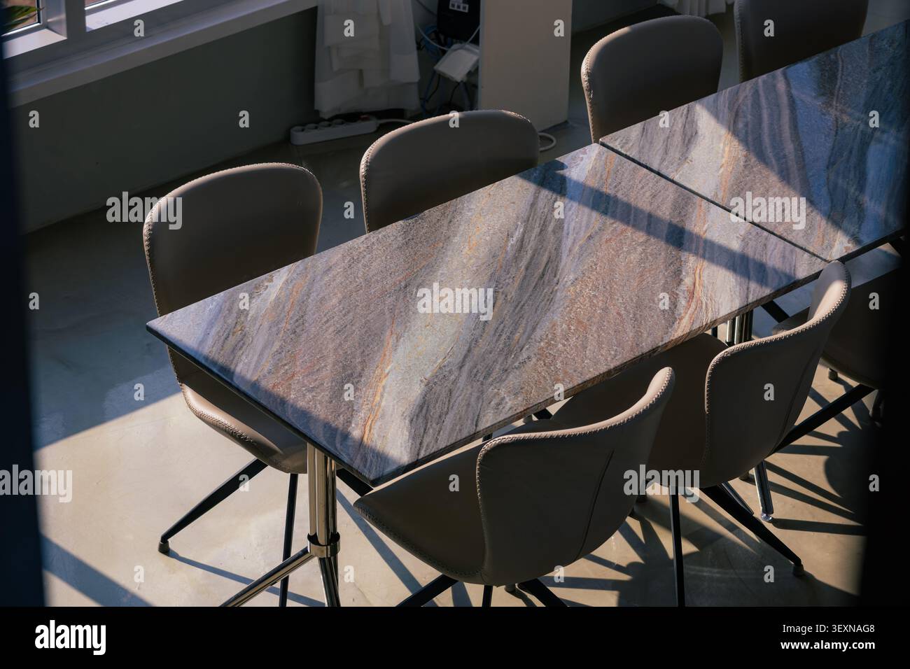 Modern Stone Table and Leather Chairs Under Dramatic Sunlight and Shadows Stock Photo