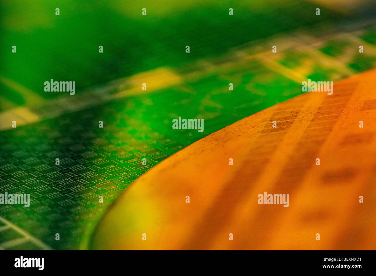Abstract green and orange patterns reflecting on a semiconductor wafer Stock Photo