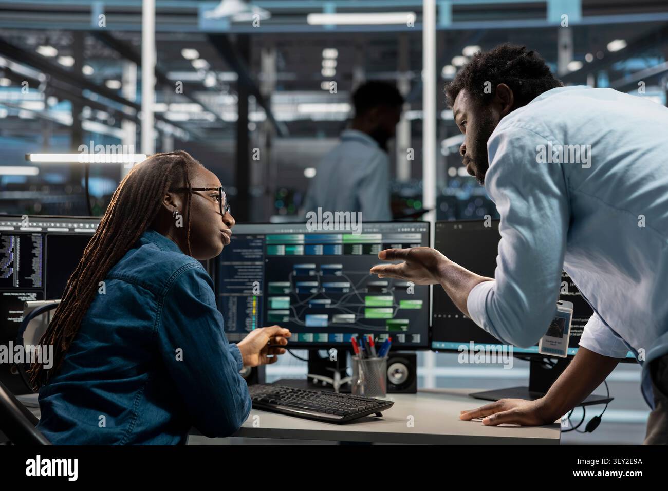 Software developers program data center equipment for machine learning training, discussing code on a PC to upgrade AI systems. Stock Photo