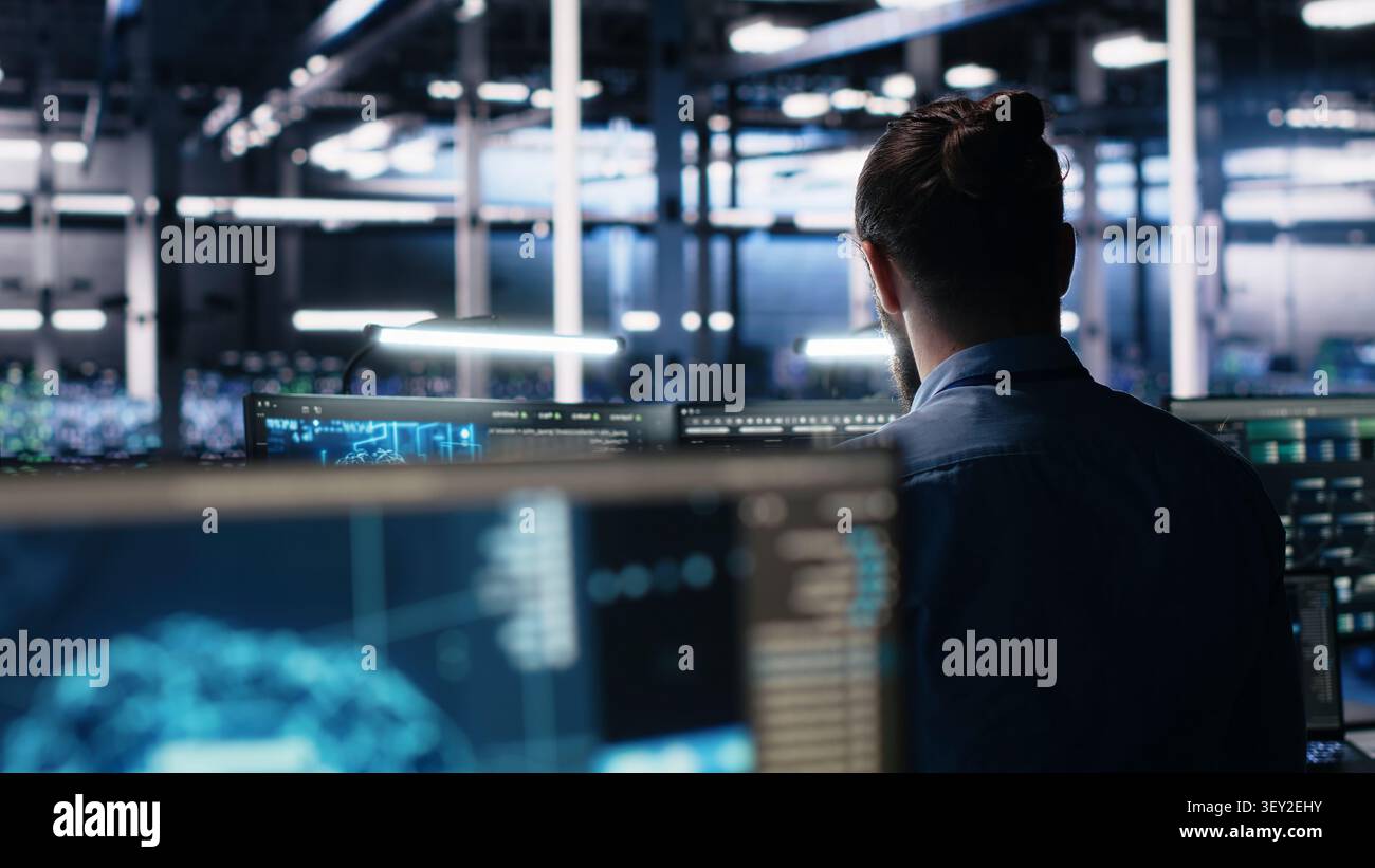 Software developer reviews artificial intelligence systems and machine learning processes inside a data center. Stock Photo