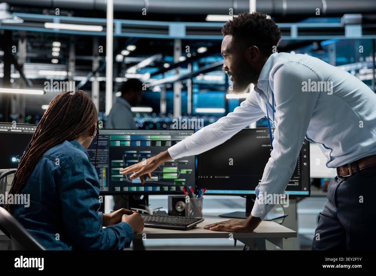 Data center supervisor gives feedback to an engineer programming equipment for machine learning training and AI system upgrades. Stock Photo