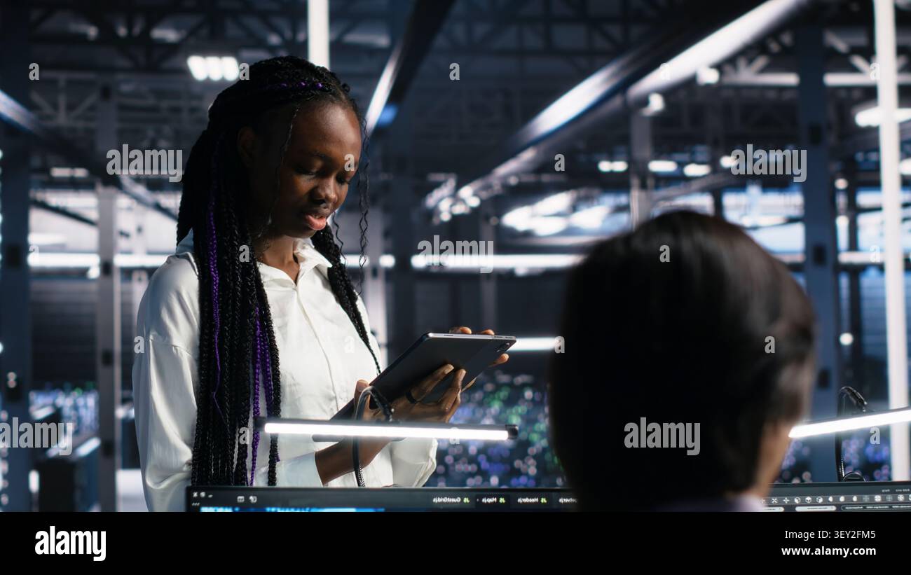 IT colleagues collaborate in a data center while reviewing AI diagnostics and infrastructure performance. Stock Photo