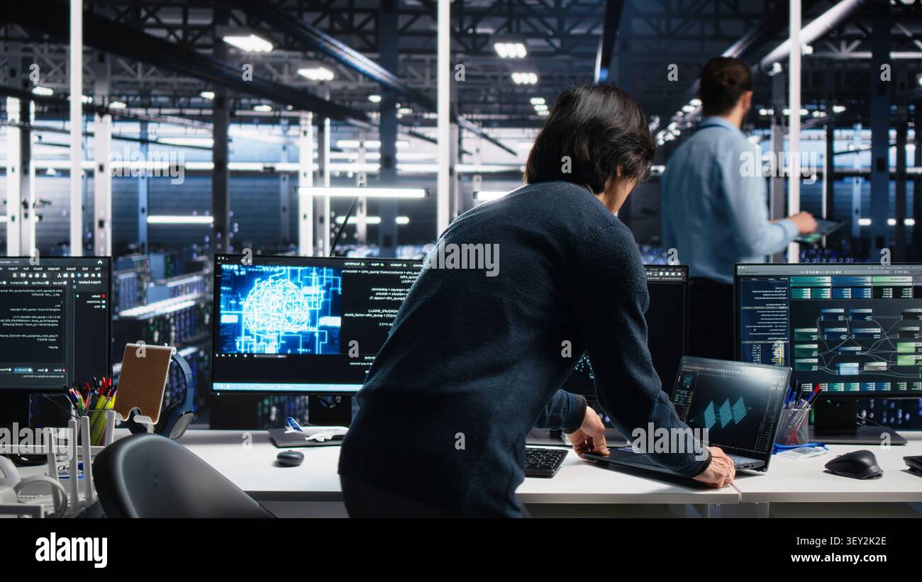 Technician programs on a computer workstation in a data center with generative AI assistance. Stock Photo