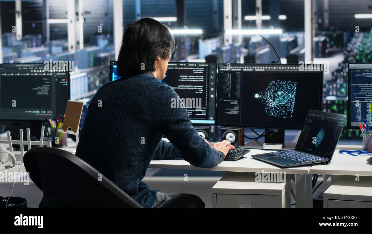 Data center technician uses laptop-based deep learning tools in a server room to improve AI operations and system efficiency. Stock Photo