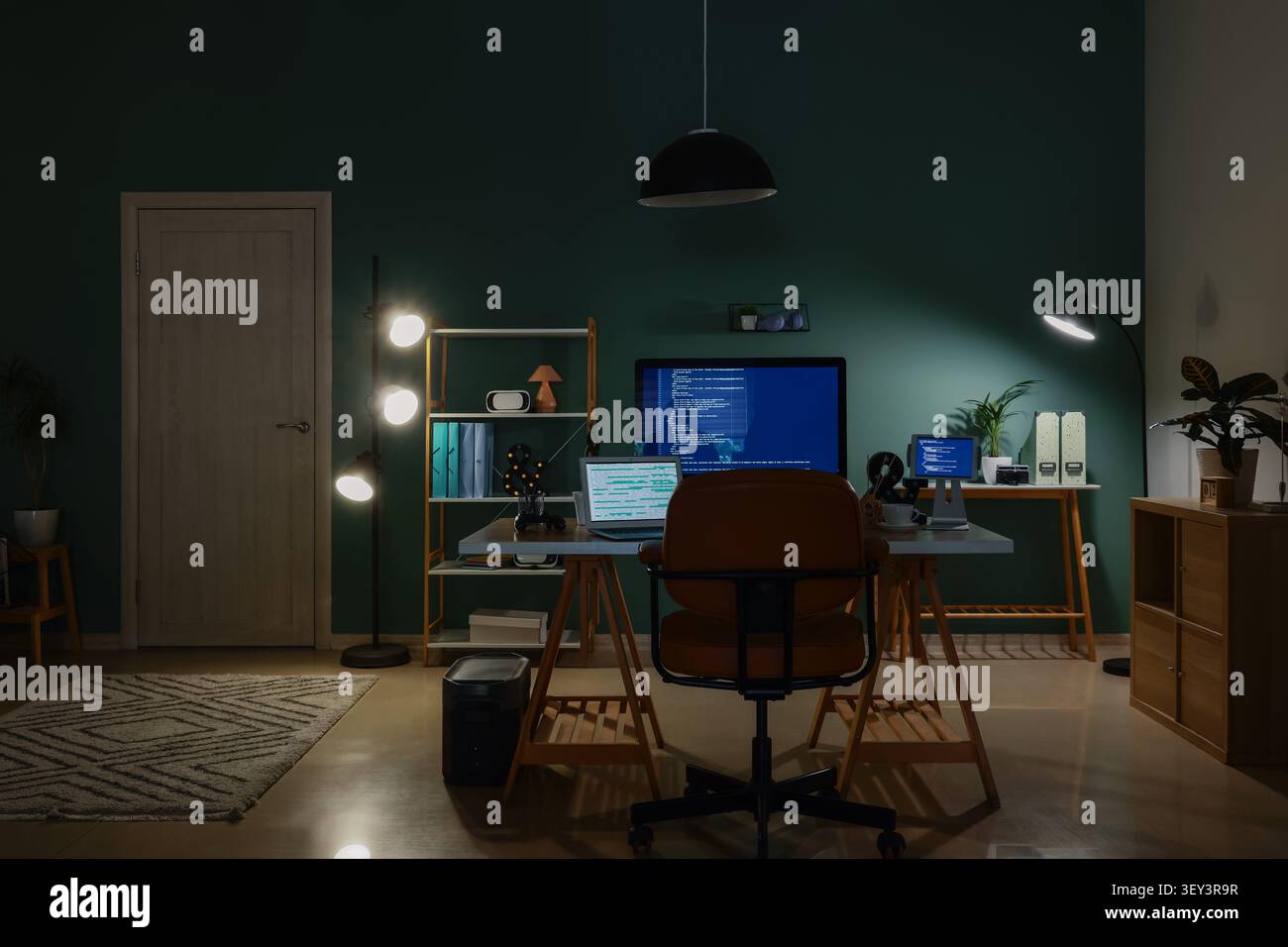 Modern home office with multiple screens displaying code Stock Photo