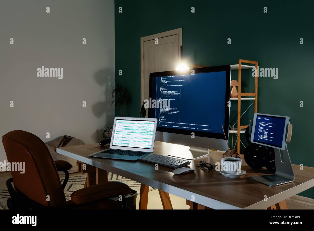 Home office desk with multiple screens displaying code Stock Photo