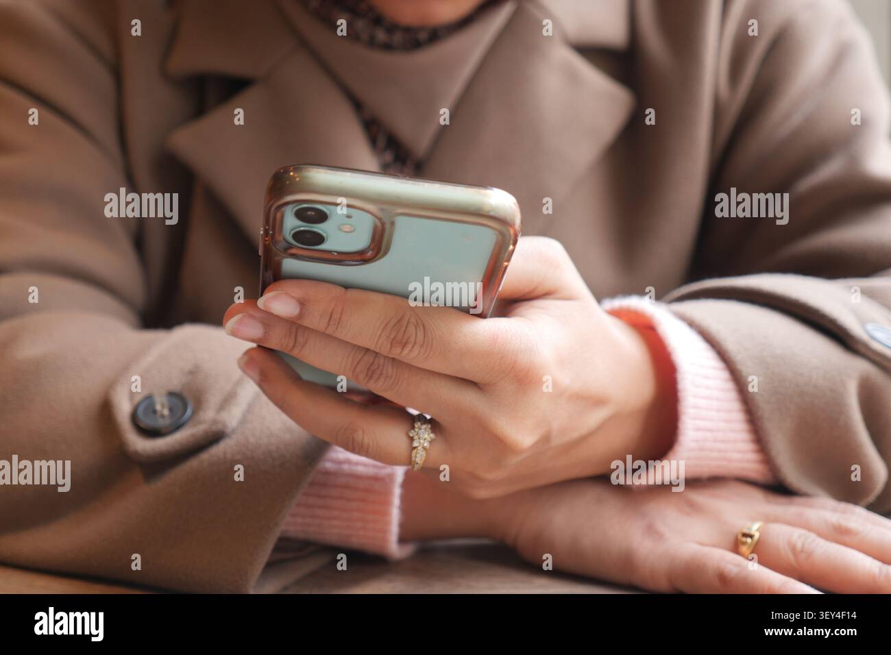 Person uses smartphone while sitting at a table Stock Photo
