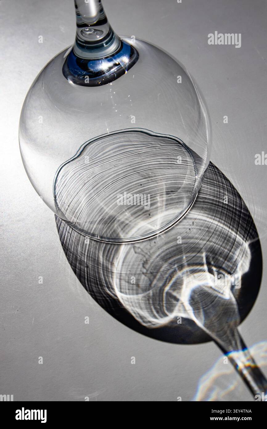 Empty wine glass with blue stem casting circular shadow on grey surface Stock Photo