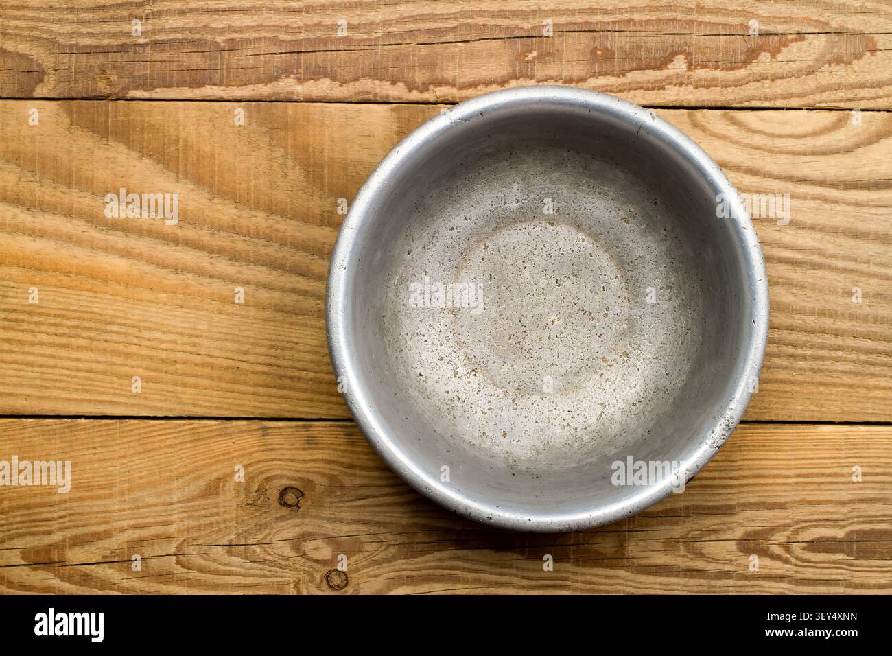 An old aluminum bowl on a background of wood. Close-up aluminum plate. Stock Photo