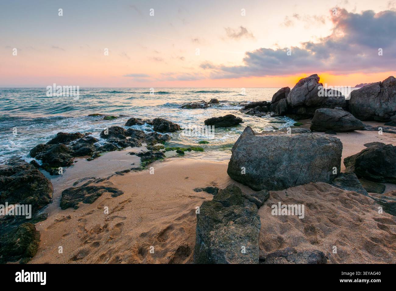 black sea landscape at sunrise. rocks on a sandy beach. sky with clouds glowing in morning light. summer vacation at the sea. bulgaria travel backgrou Stock Photo
