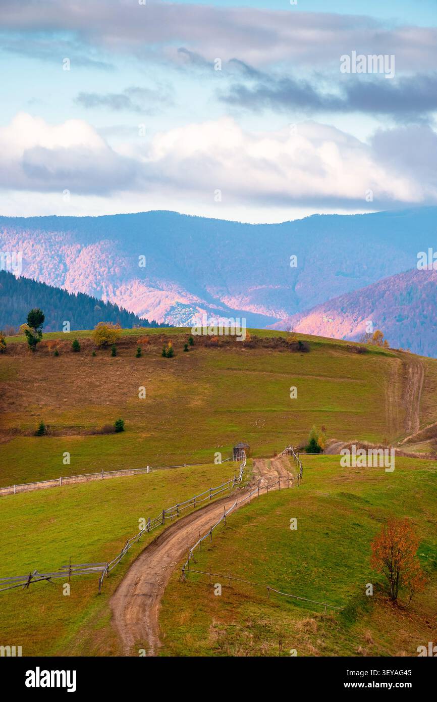winding rural dirt path through hill. rolling countryside of ukraine in fall color. cloudy morning sky. carpathian mountains in autumn Stock Photo