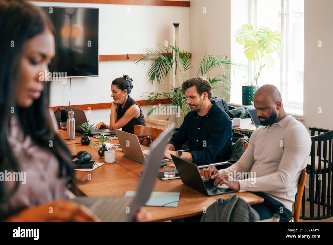 Friendly corporate team working on laptops at shared workspace Stock Photo