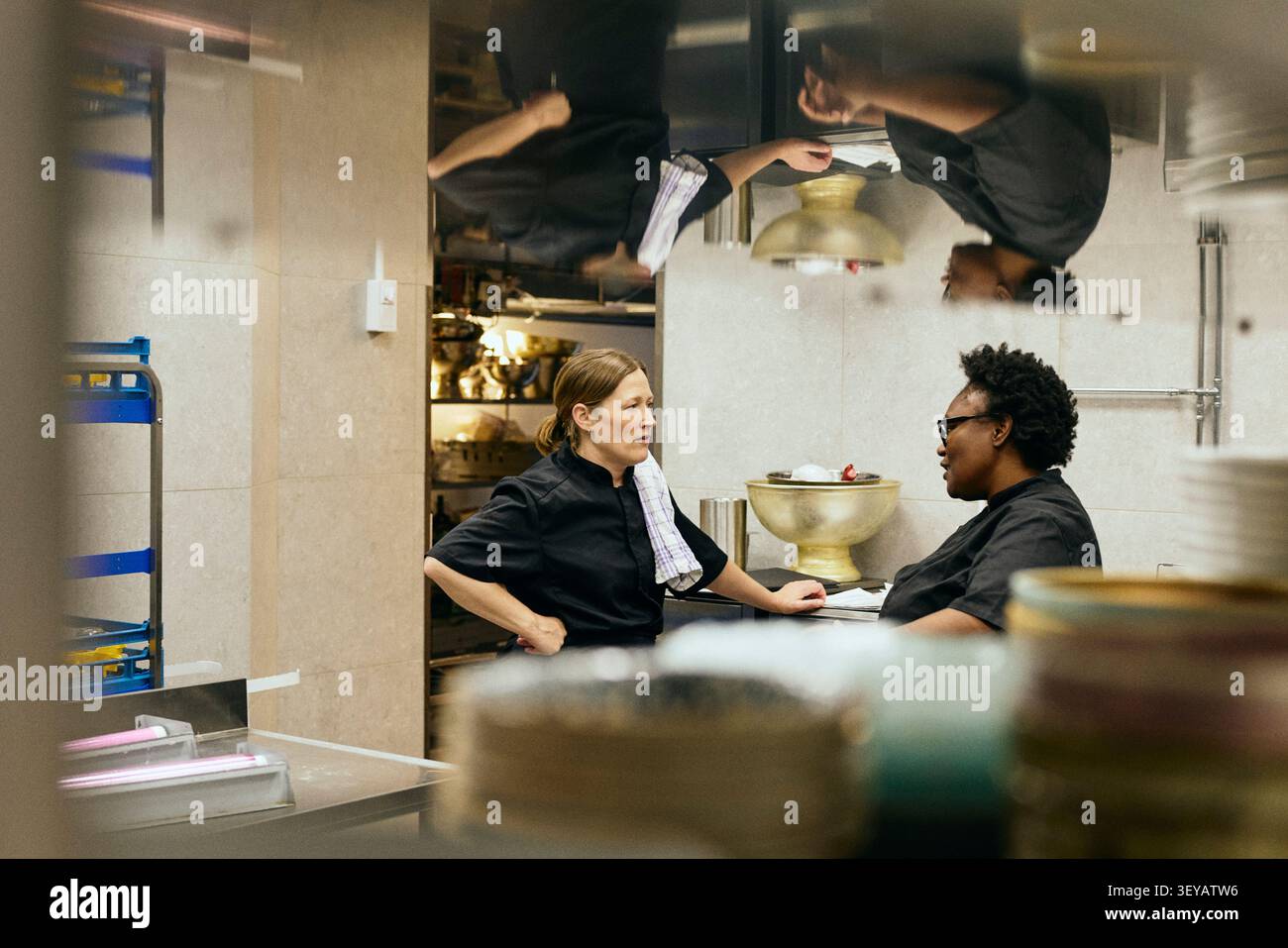 Two female chefs chatting during their shift in restaurant kitchen Stock Photo