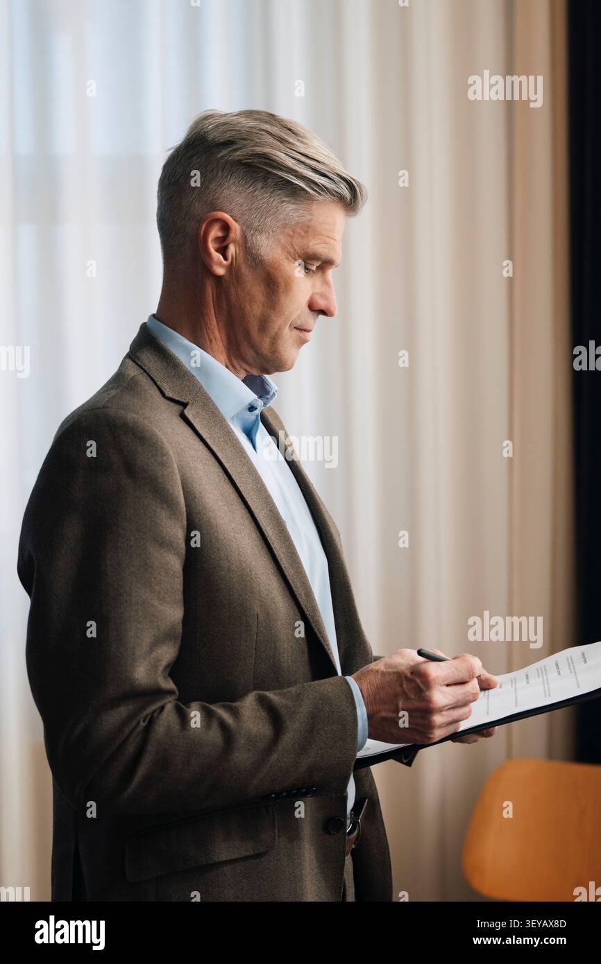 Senior businessman going through paperwork and documents at office Stock Photo