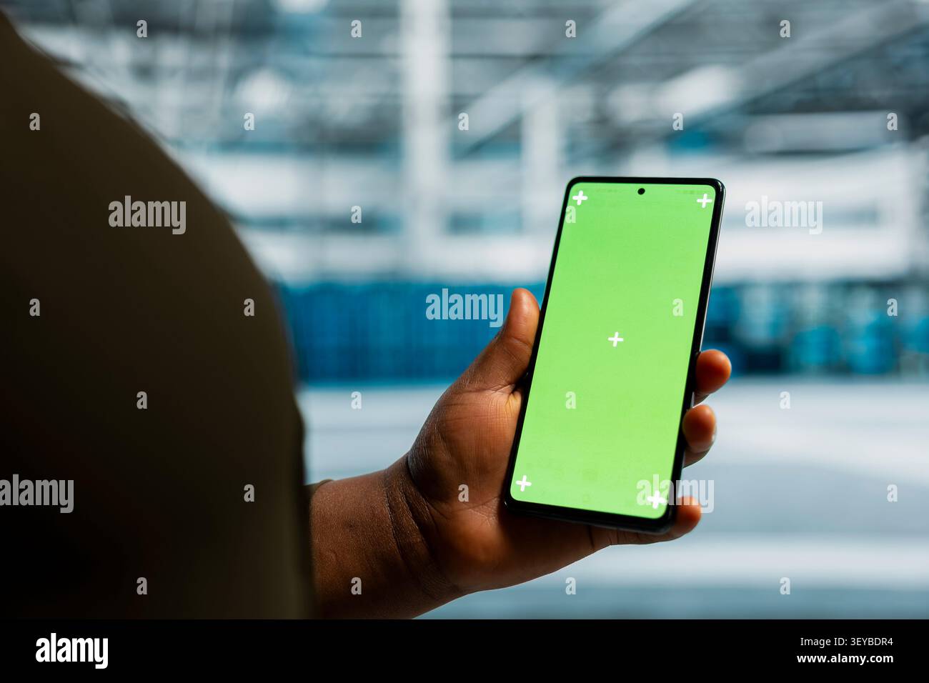 Data center administrator works with a chroma key smartphone, using an editable screen to review performance data. Stock Photo