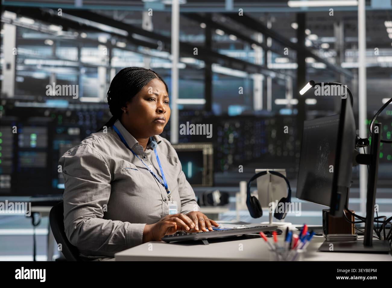 Server facility software engineer works with workstation to update servers tech, setting up equipment working with program. Stock Photo