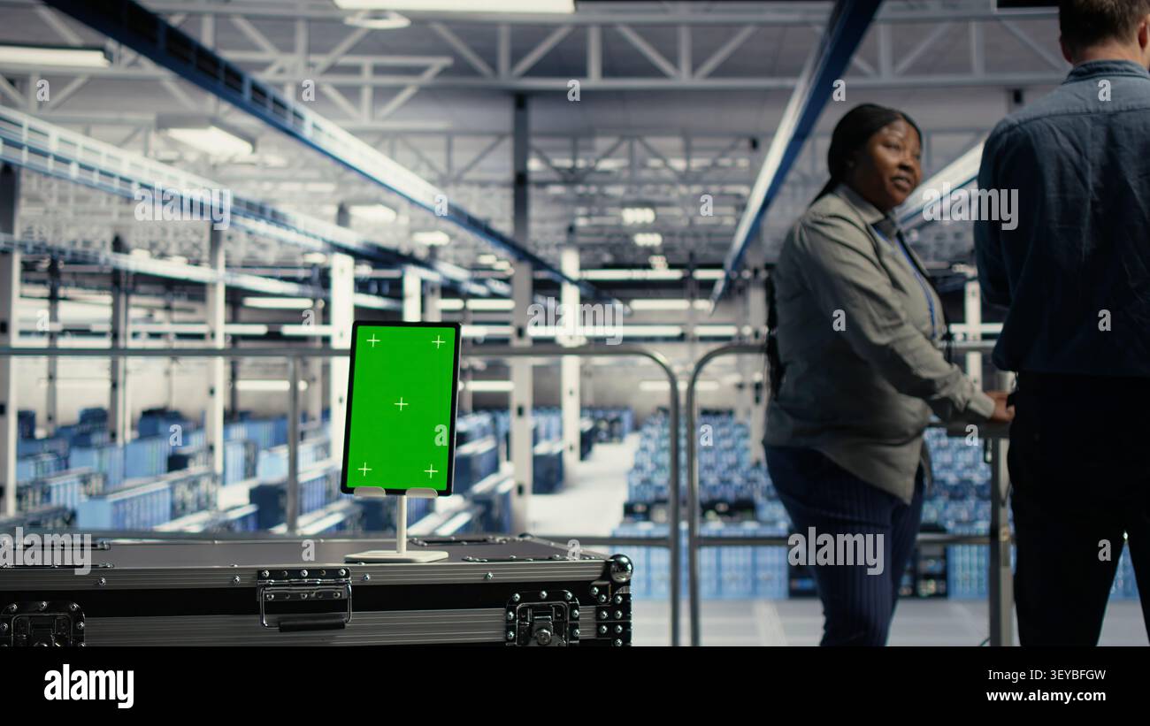 Data center worker works with a chroma key tablet, using an editable screen to manage machine learning workloads. Stock Photo