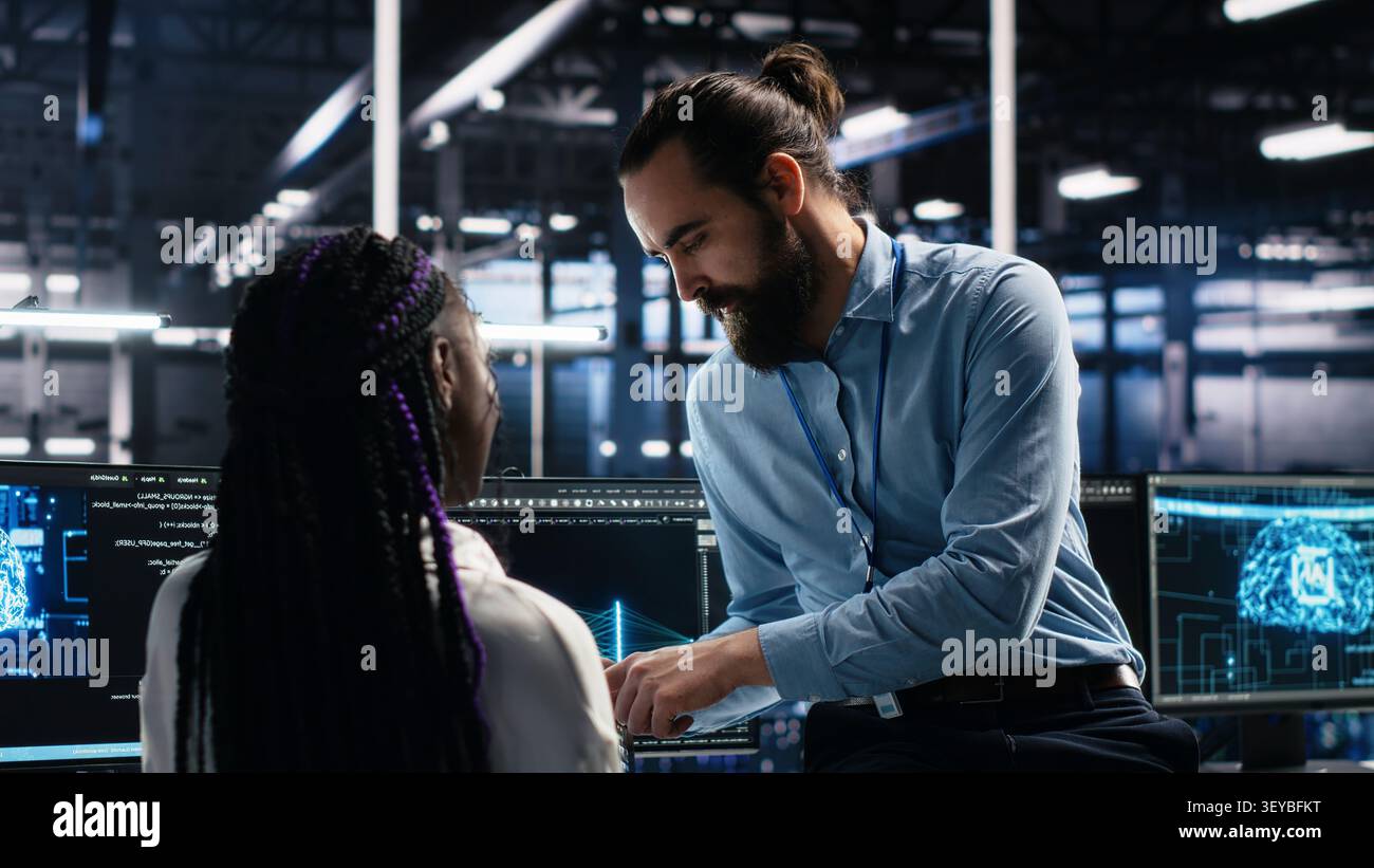 System administrator and employee programs on a computer workstation in a server hub with generative AI assistance. Stock Photo