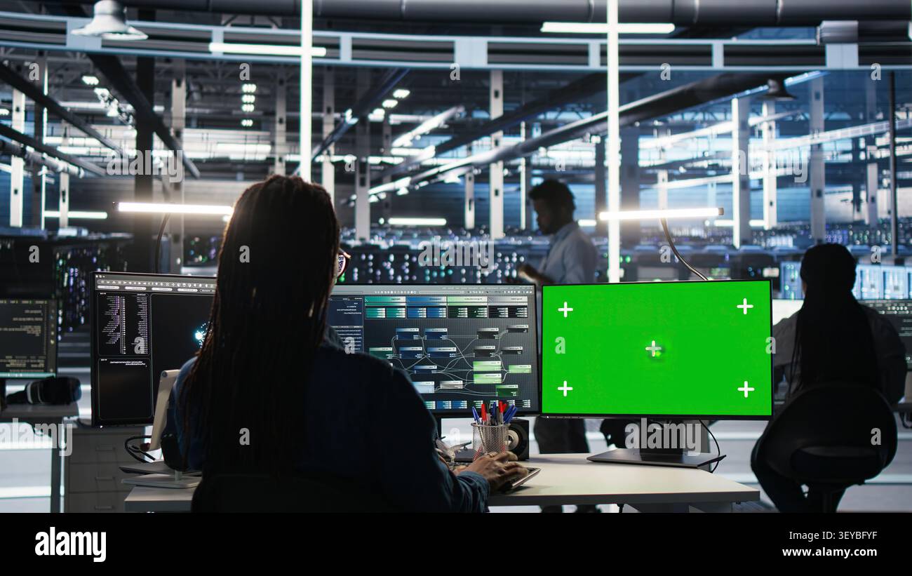 Engineer uses a green screen computer in a server farm to categorize unstructured data with node tree systems. Stock Photo