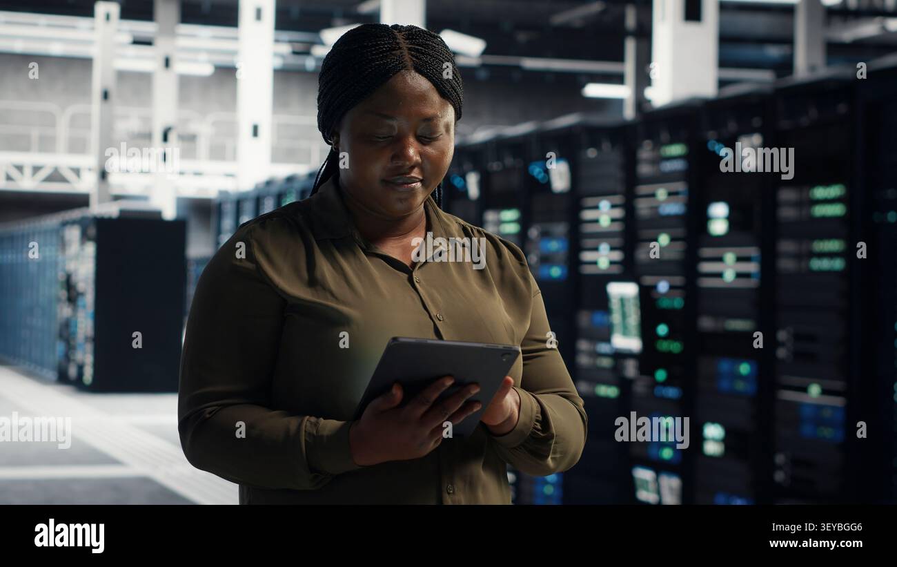 Technical specialist working with digital tablet in server facility, integrating new technologies and systems. Stock Photo