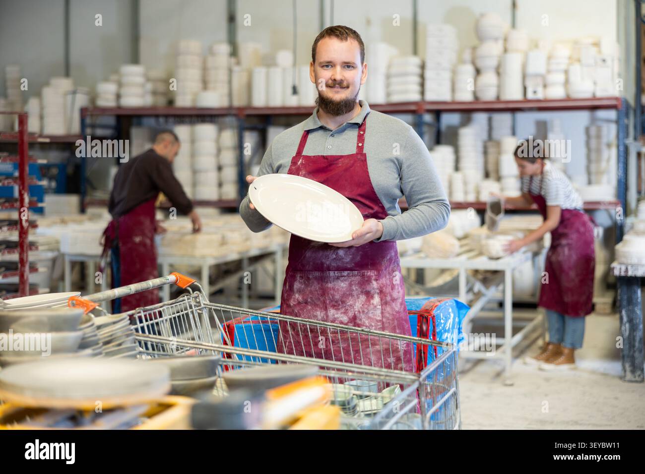 Enthusiastic ceramicist demonstrating handcrafted plates in ceramic studio Stock Photo