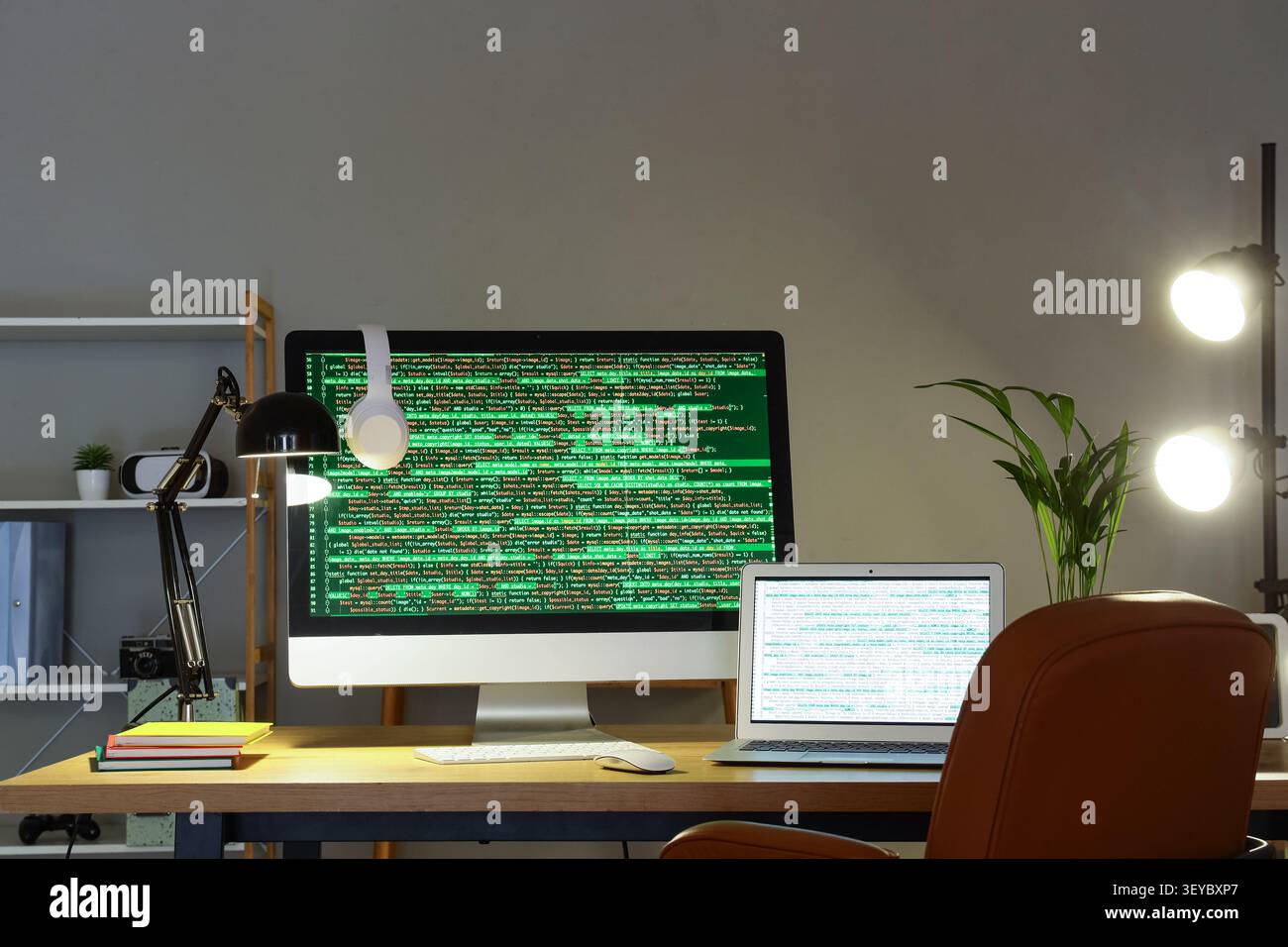 Modern workspace with desktop and laptop displaying code Stock Photo