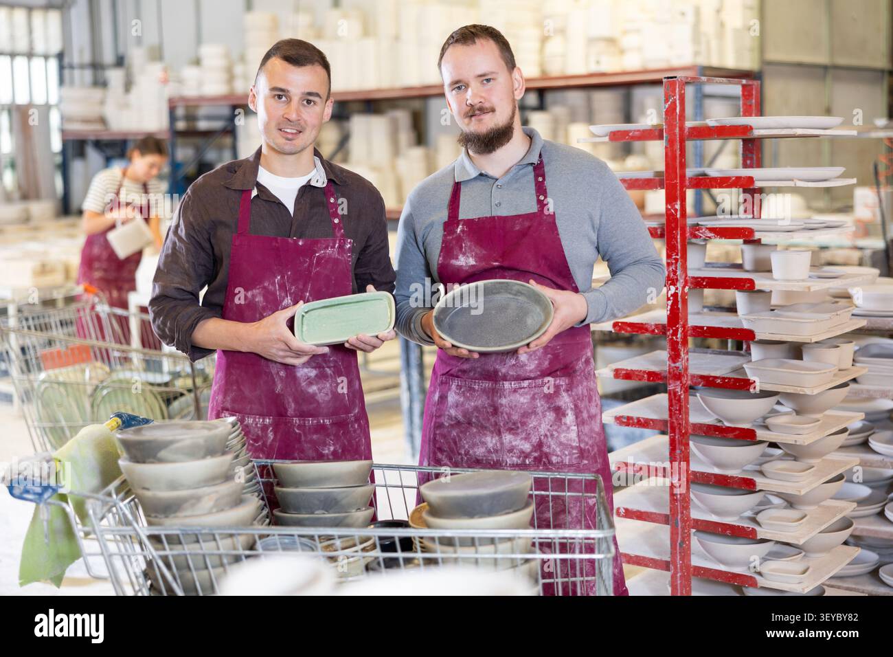 Two potters holding handcrafted ceramic plates in pottery workshop Stock Photo