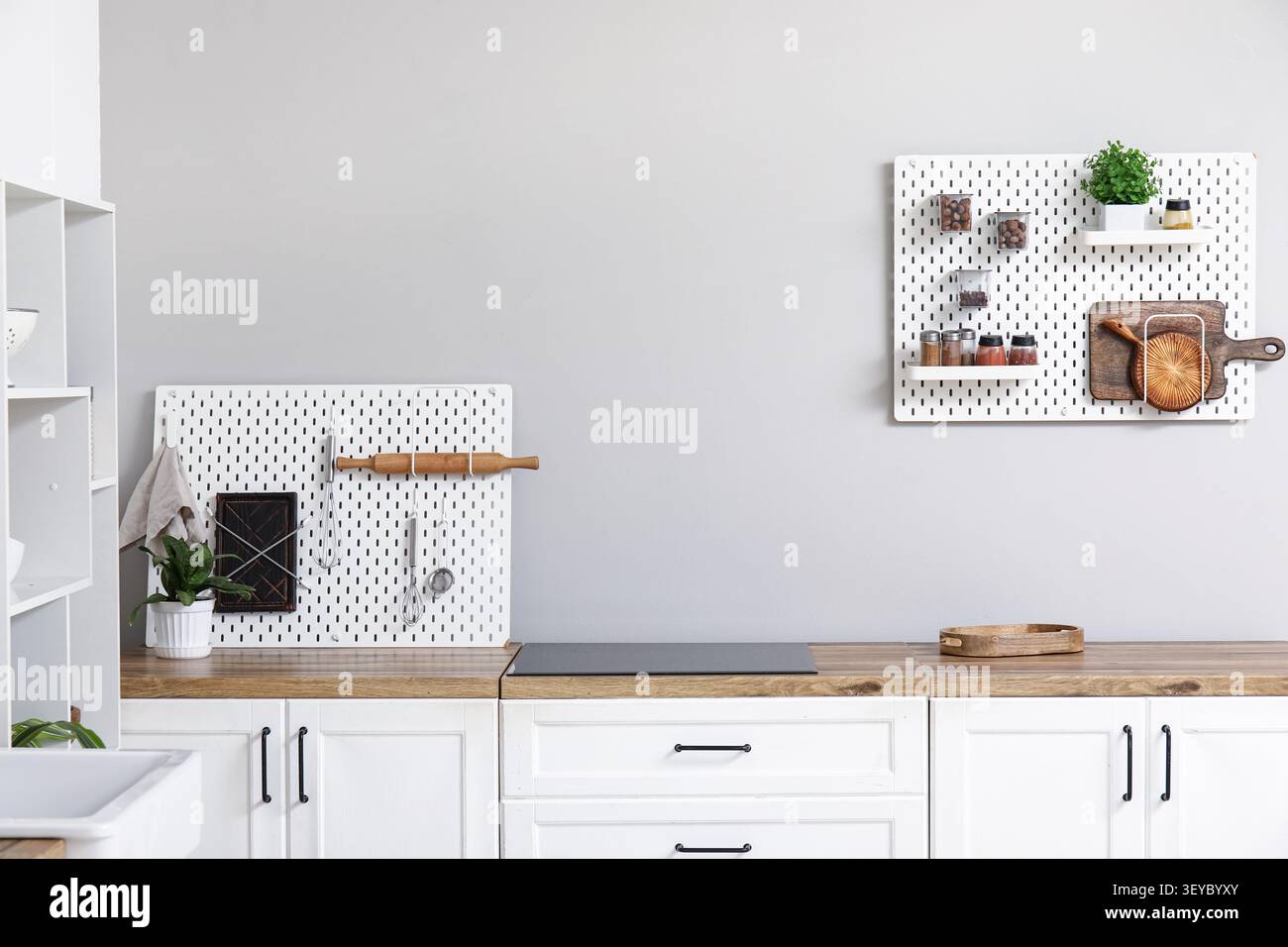 Stylish light kitchen with pegboards and kitchenware Stock Photo
