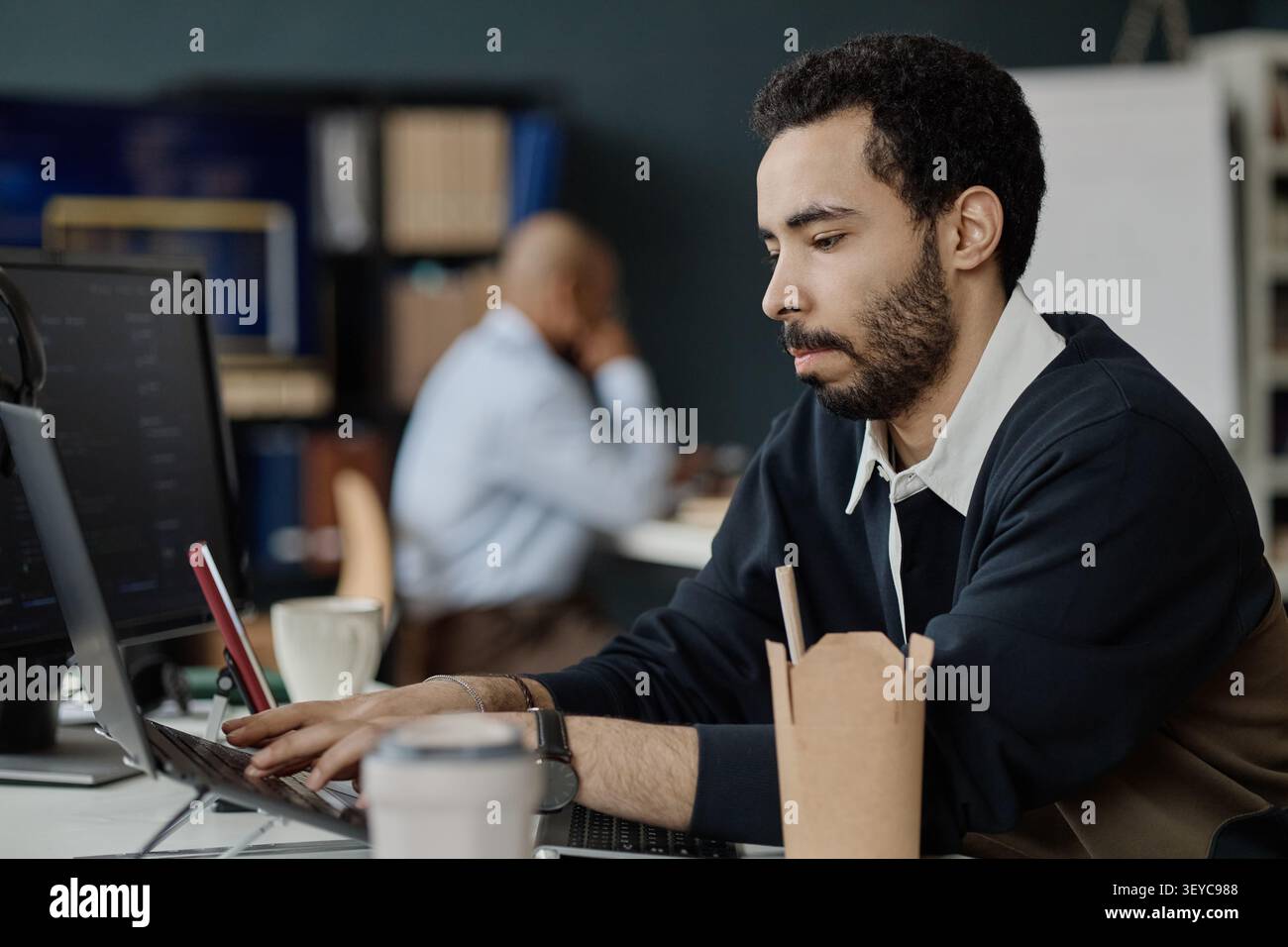 Man Using Laptop for Software Tasks in Information Office Stock Photo