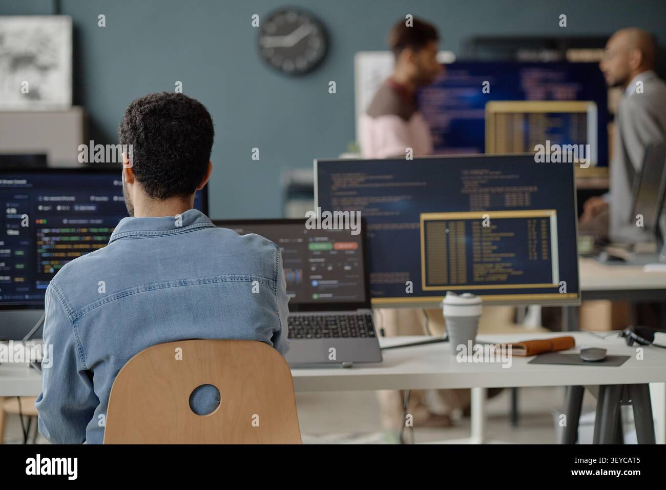 Adult Man Coding at Multiple Monitors in Information Technology Office Stock Photo