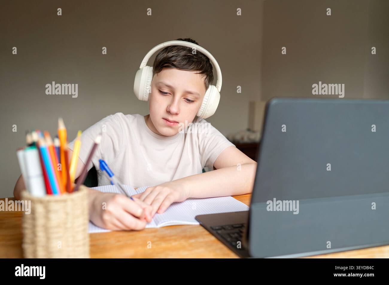 Focused schoolboy concentrating on homework during online class Stock Photo