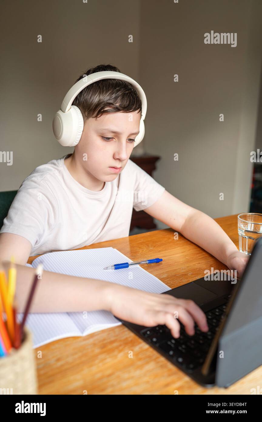 Schoolboy using laptop during online lesson at home Stock Photo