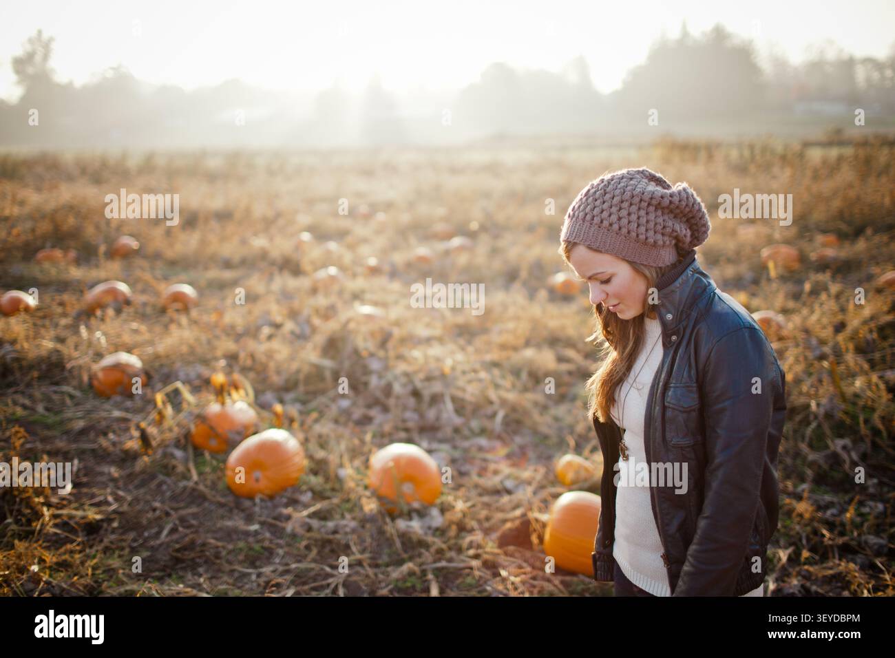 Young woman looking down thoughtfully in a pumpkin patch Stock Photo