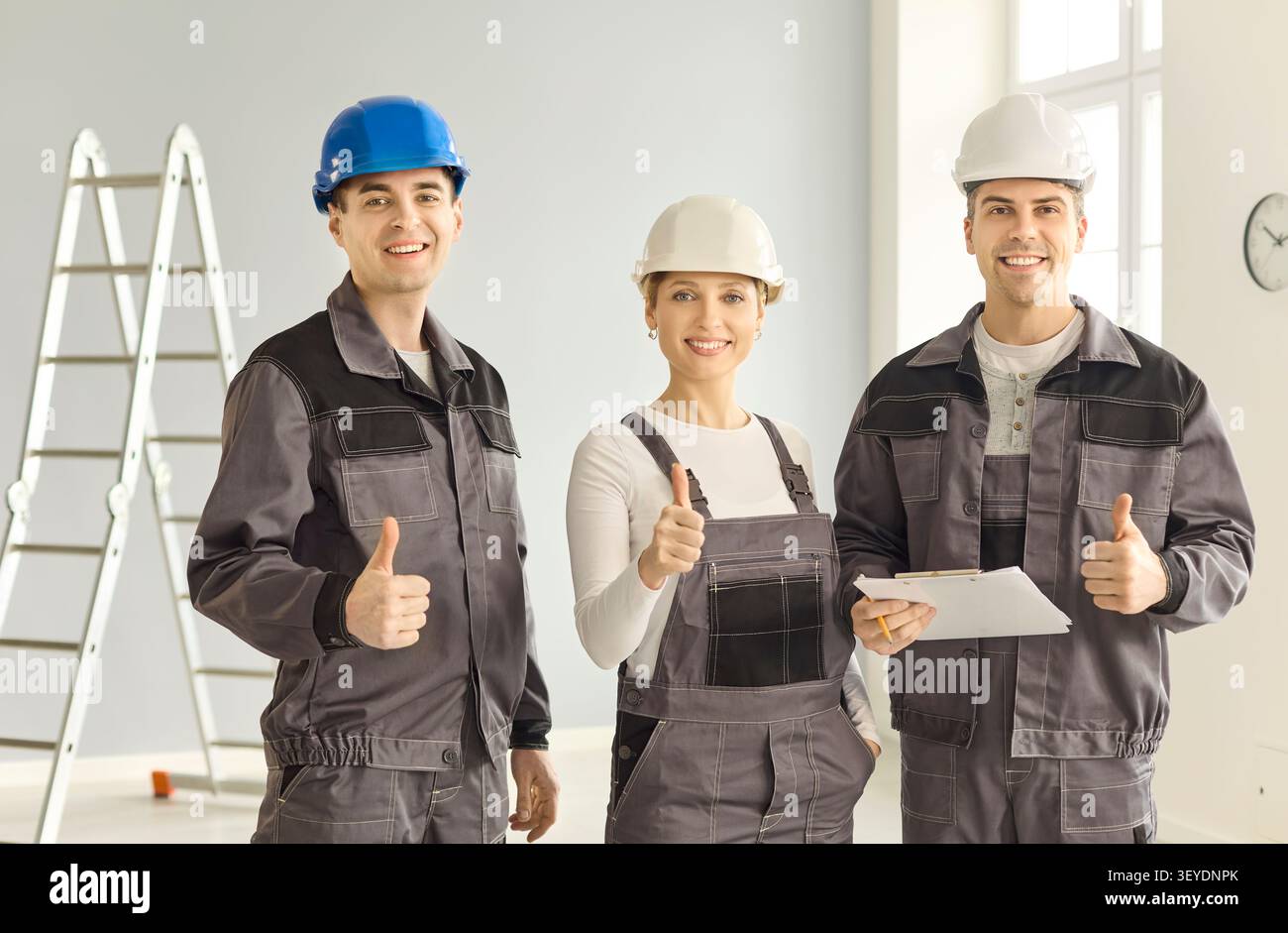 Confident construction workers team with helmets giving thumbs up on site Stock Photo