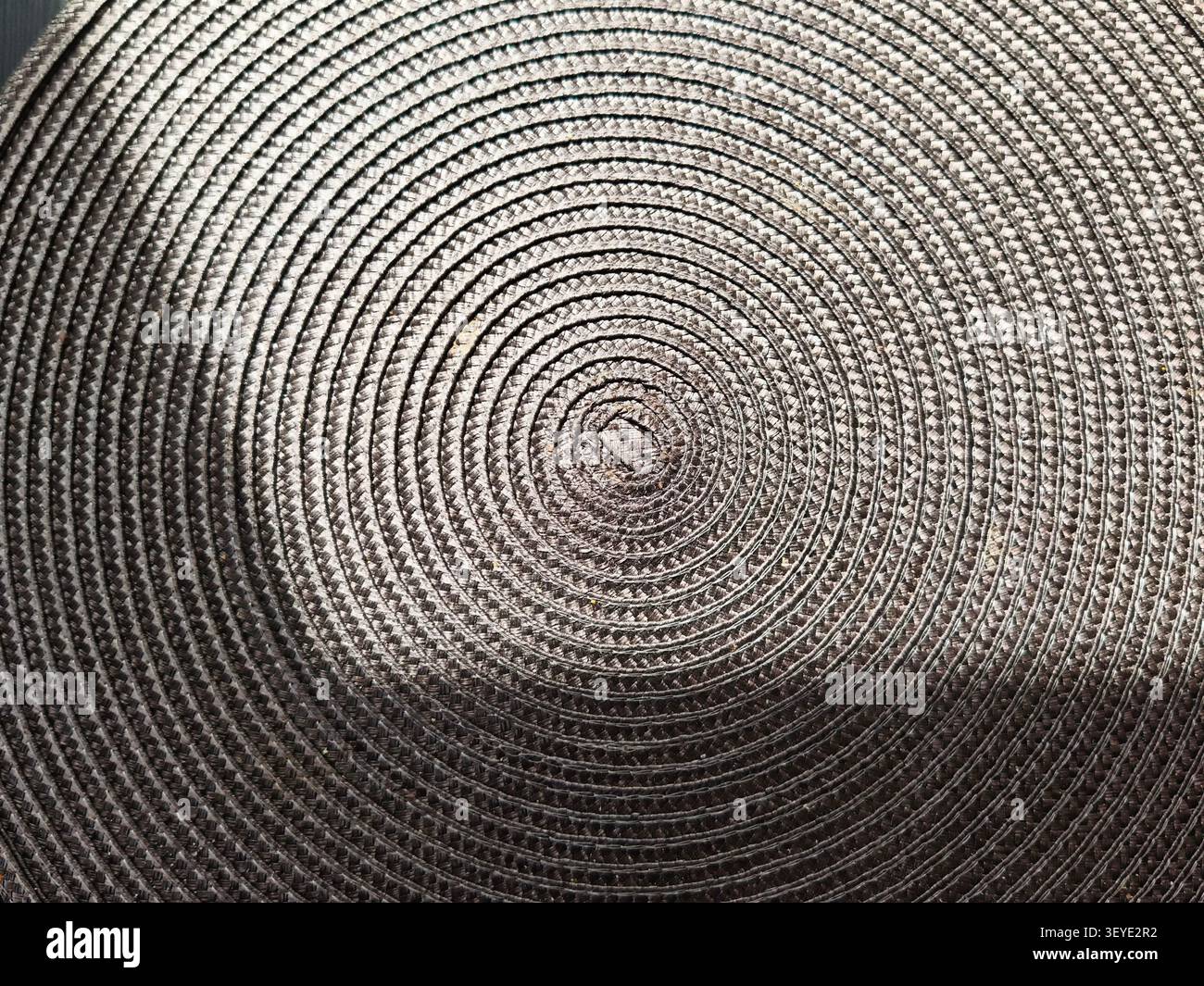 A close view of a circular woven texture showing uniform lines and patterns, set against a plain background that allows for additional text. Stock Photo