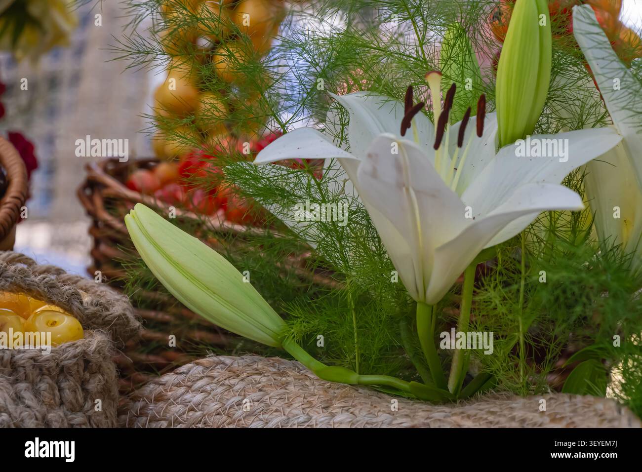 Elegant white lily surrounded by fresh cherries, greenery and rustic decorations creating a beautiful summer floral arrangement with natural seasonal Stock Photo