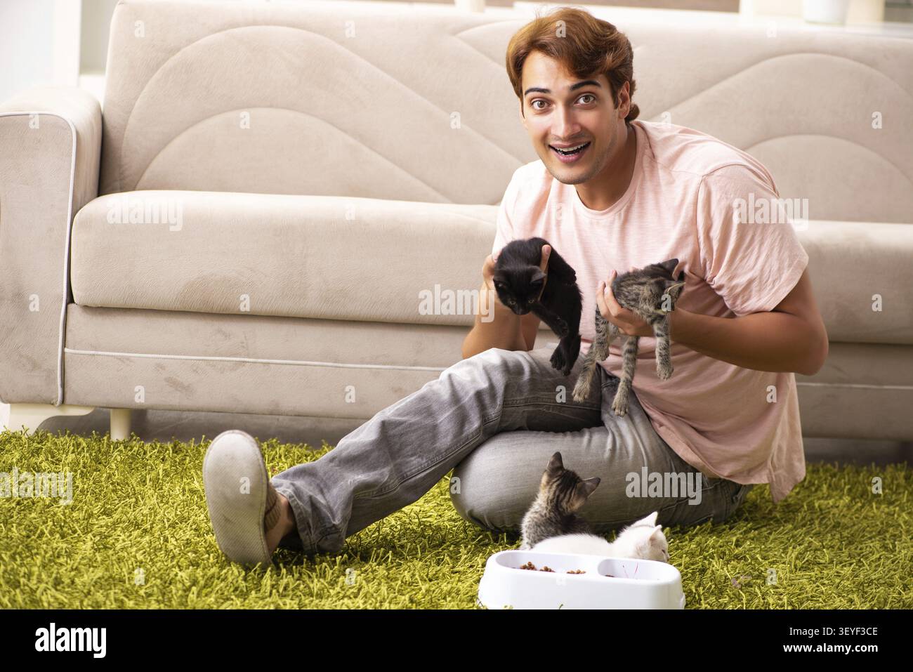 Young man playing with kitten at home Stock Photo