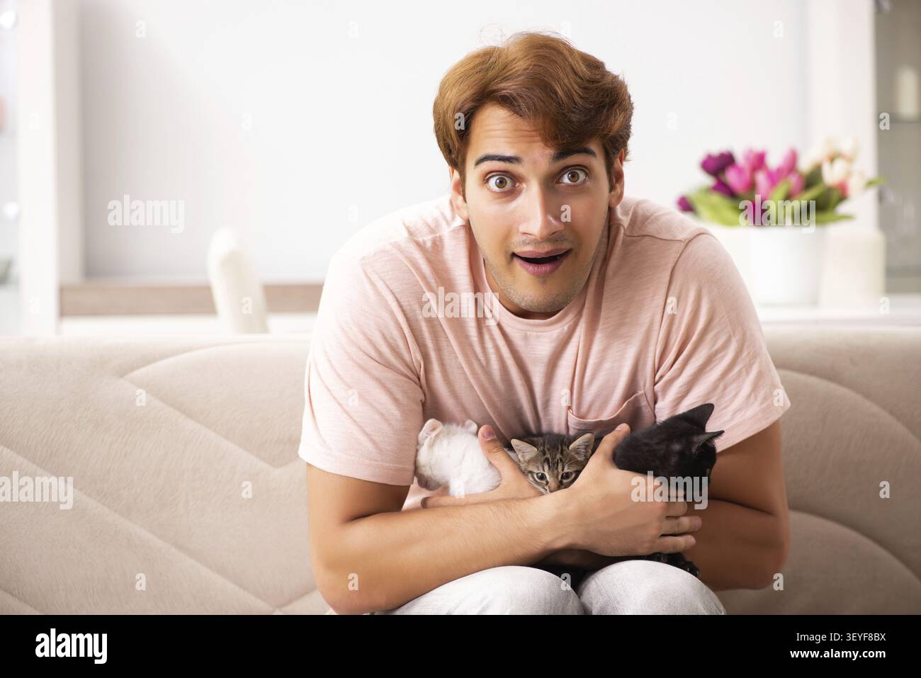 Young man playing with kitten at home Stock Photo