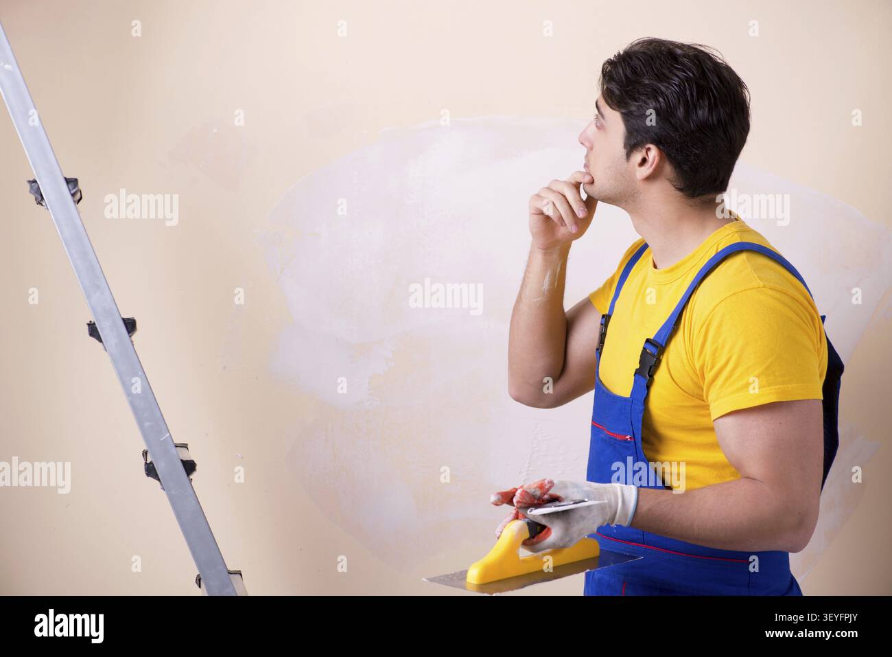 Young contractor employee applying plaster on wall Stock Photo
