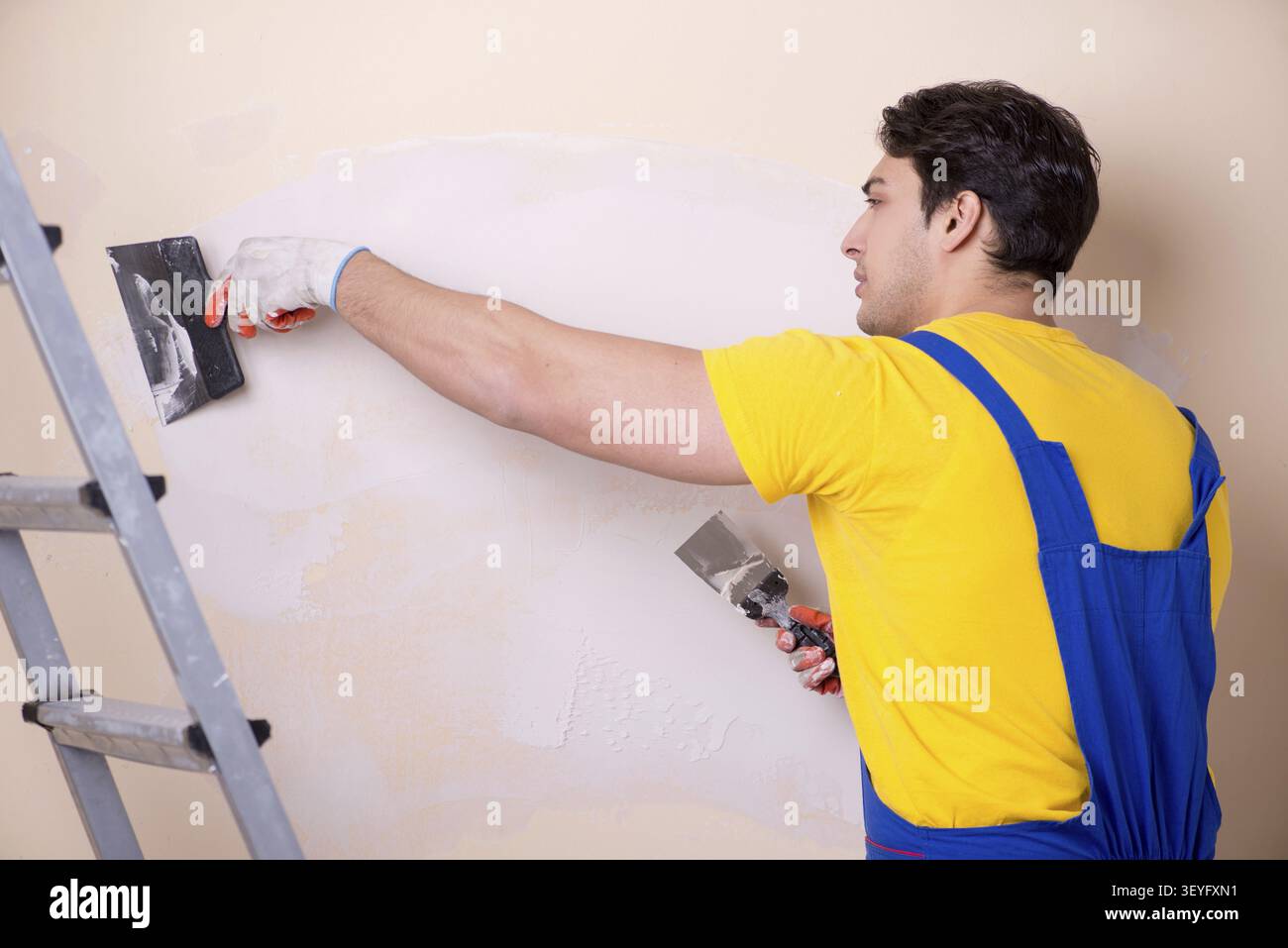 Young contractor employee applying plaster on wall Stock Photo