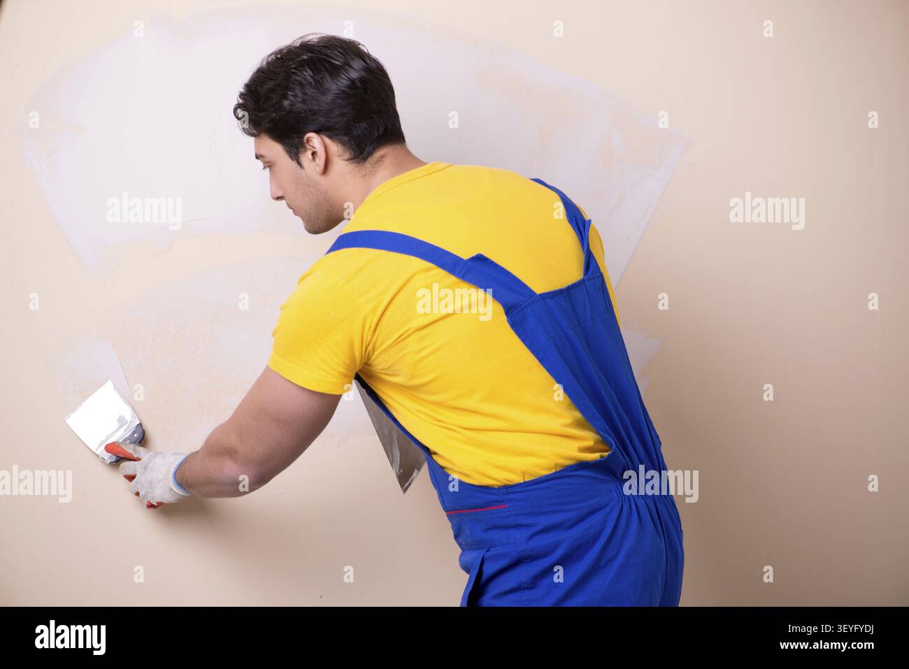 Young contractor employee applying plaster on wall Stock Photo