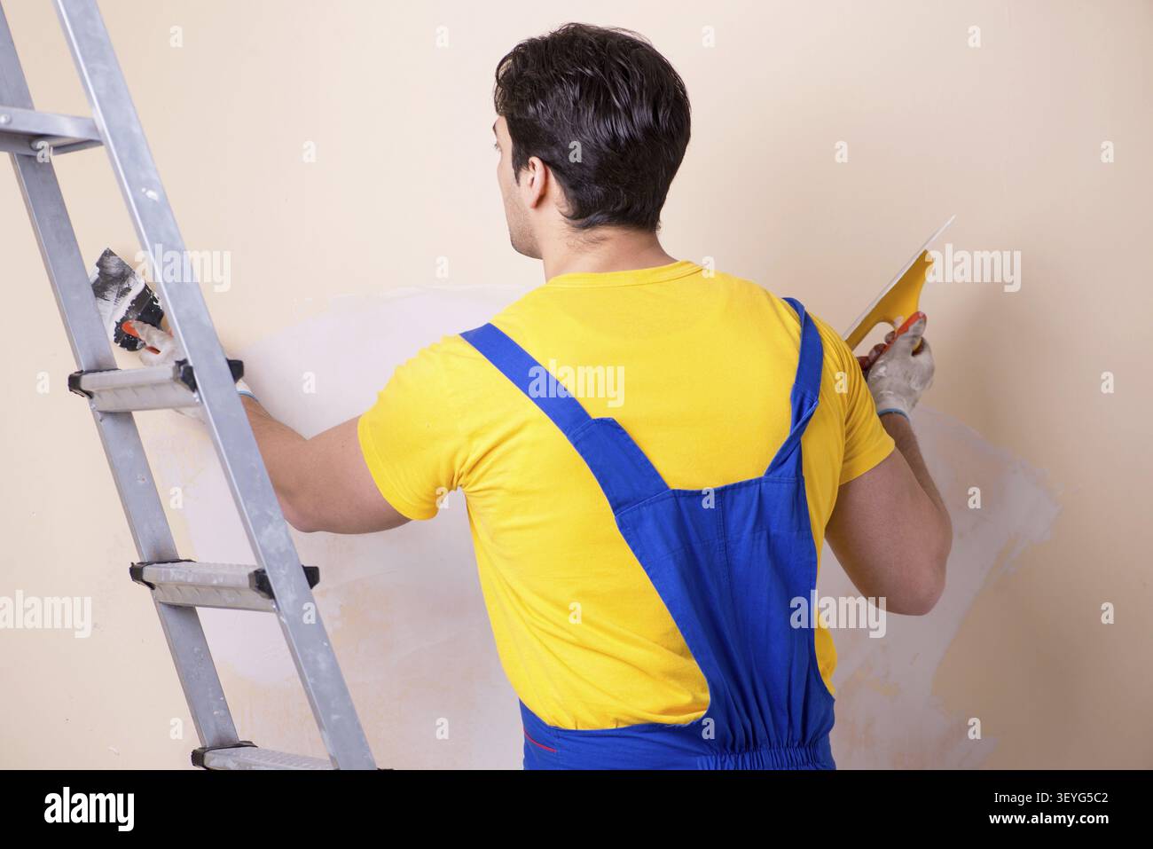 Young contractor employee applying plaster on wall Stock Photo