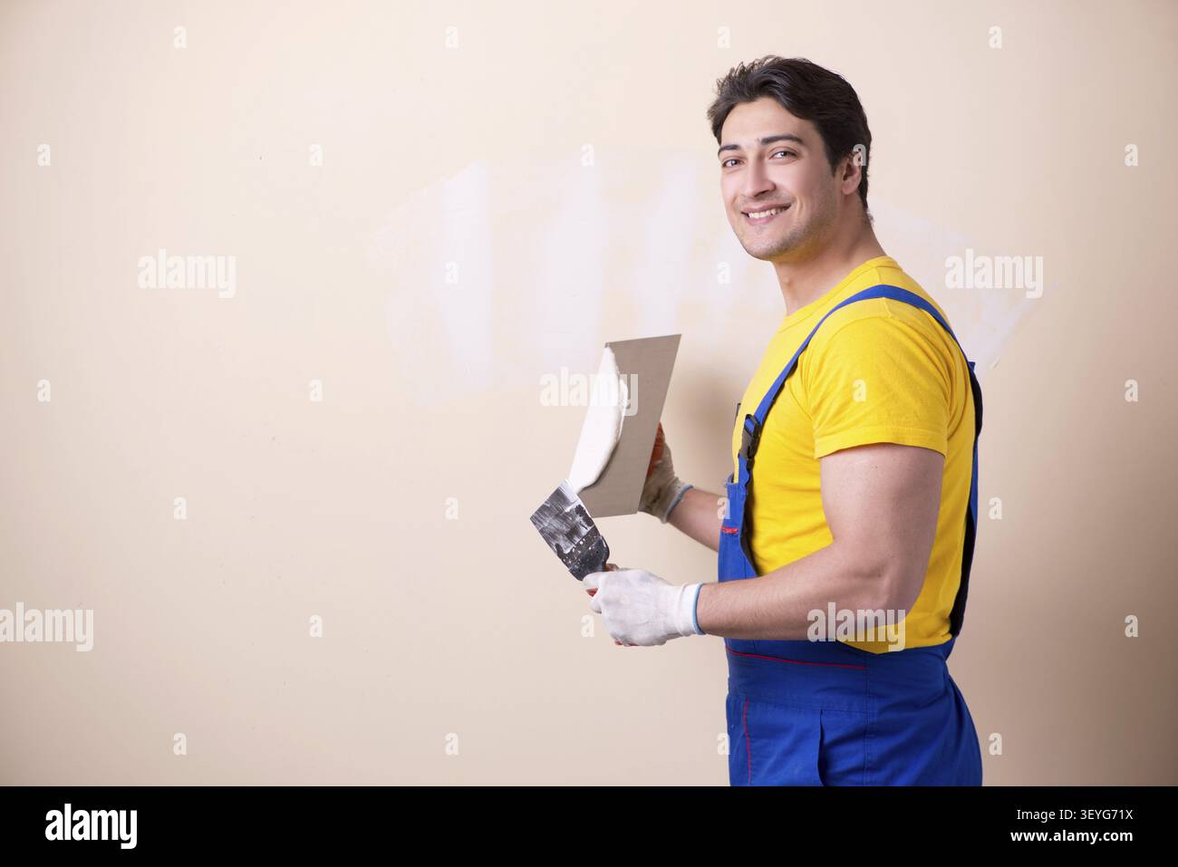 Young contractor employee applying plaster on wall Stock Photo