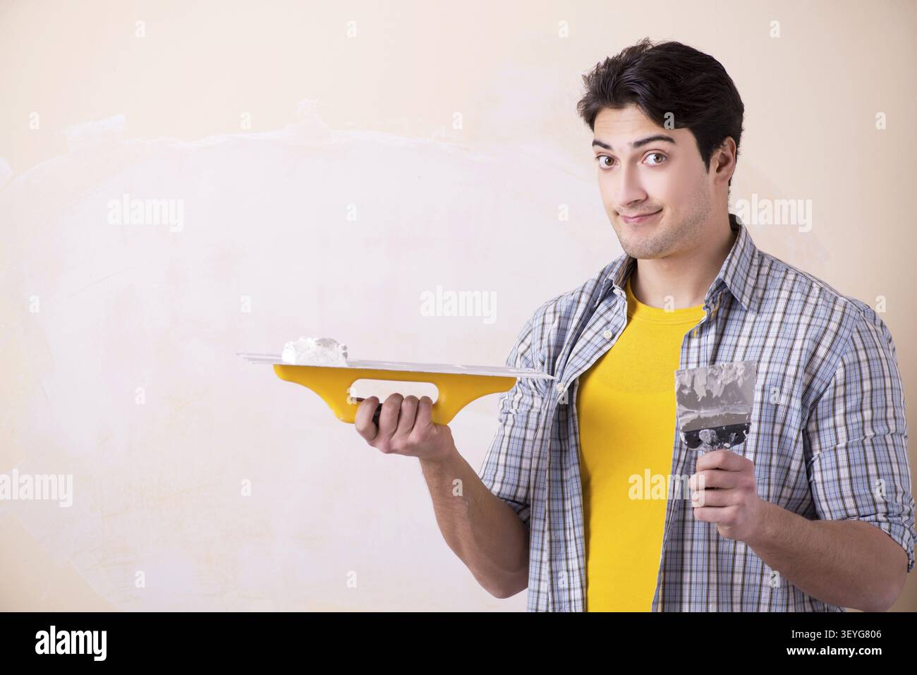 Young man applying plaster on wall at home Stock Photo