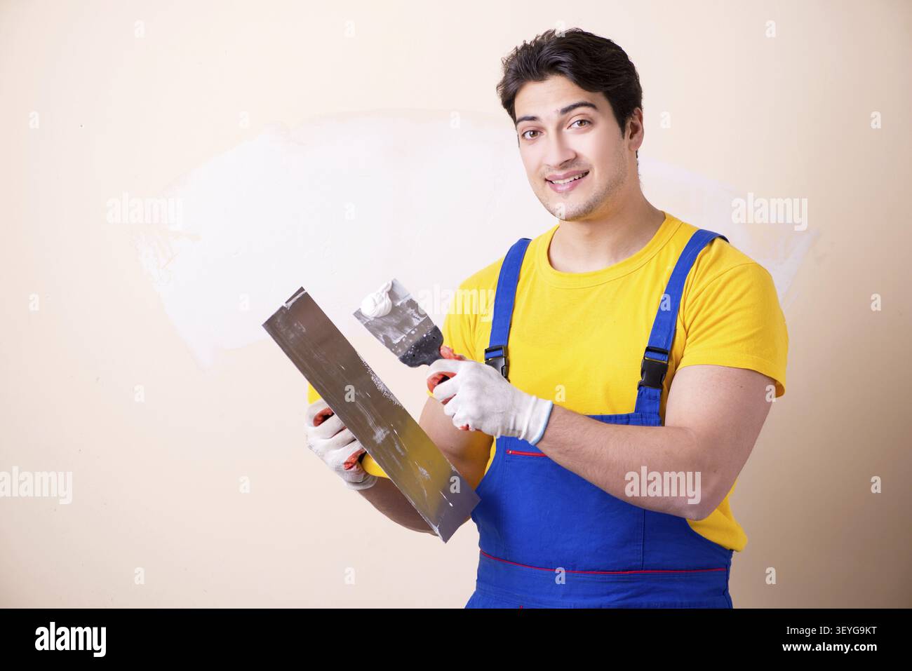 Young contractor employee applying plaster on wall Stock Photo