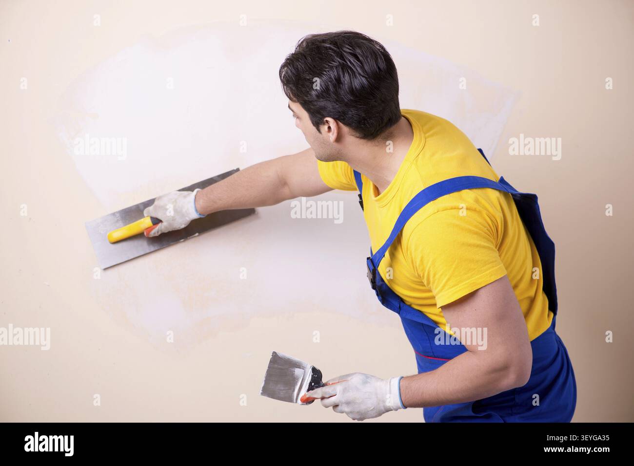 Young contractor employee applying plaster on wall Stock Photo