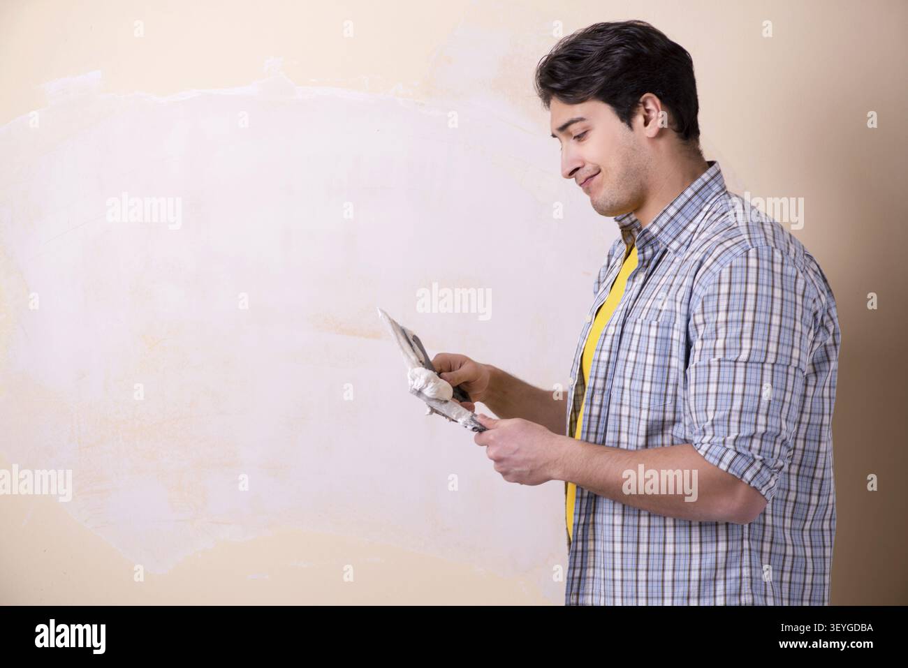 Young man applying plaster on wall at home Stock Photo